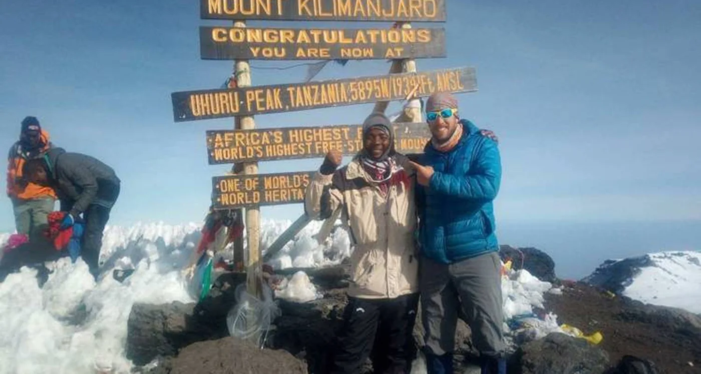 Climbers beside the Uhuru Peak sign